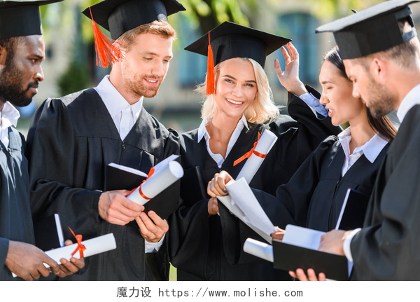 身穿博士服的毕业生微笑的多民族毕业学生在海角与文凭